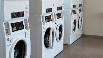 A row of stacked front-loading washing machines in a commercial laundry room.