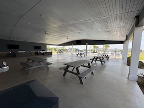 An outdoor covered patio area with picnic tables and seating. - RV Resort, Back-In Full Hookup, 3 Pools, Snowbirds, Kids, Pets (Foley)