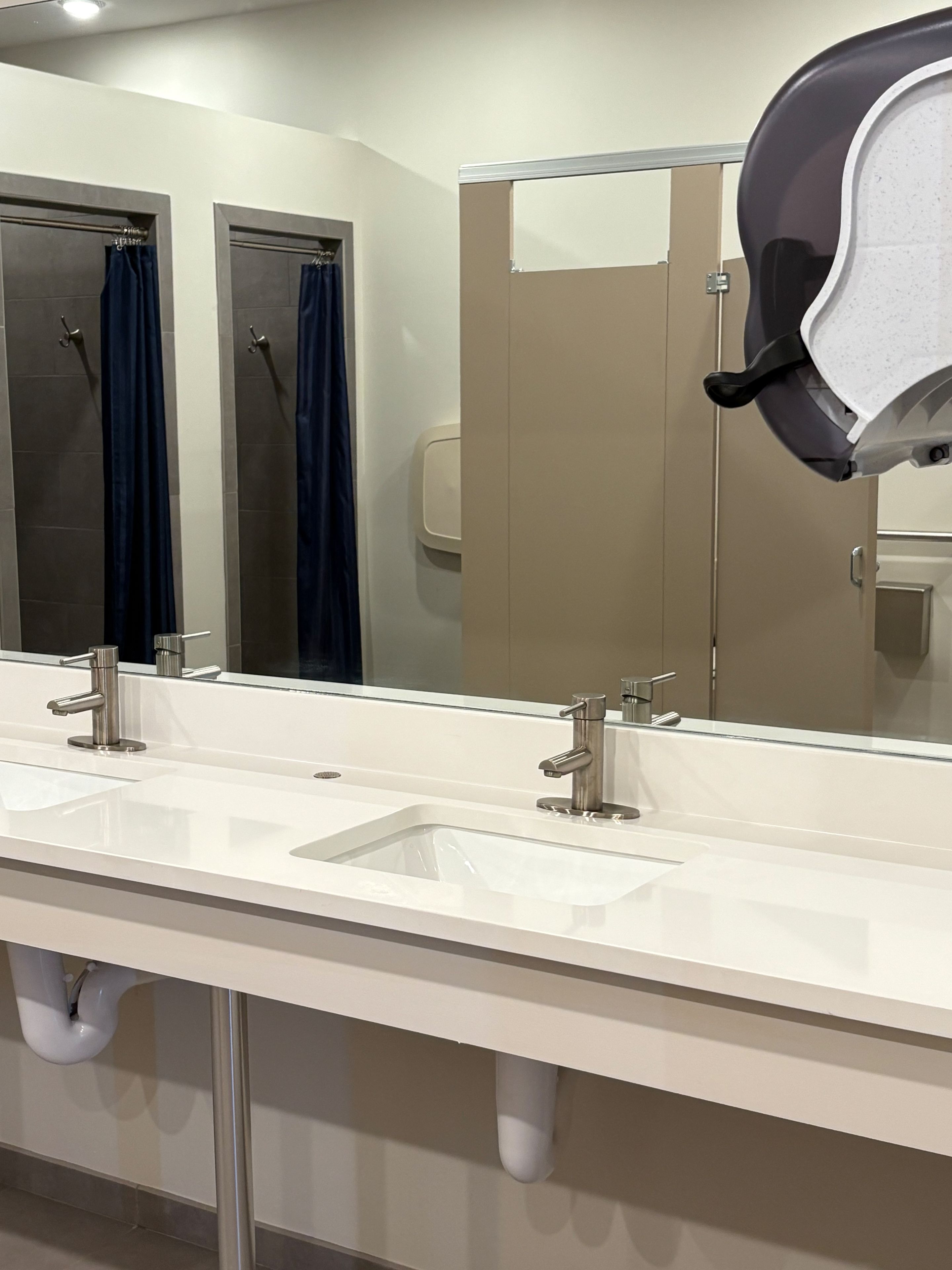 Une salle de bain moderne avec deux lavabos, un grand miroir et un sèche-mains.