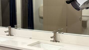 Une salle de bain moderne avec deux lavabos, un grand miroir et un sèche-mains.