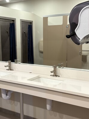 A modern bathroom with two sinks, a large mirror, and a hand dryer.