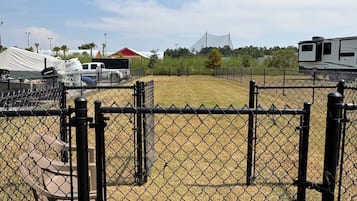 A fenced area with a tent and a vehicle, likely a campsite.
