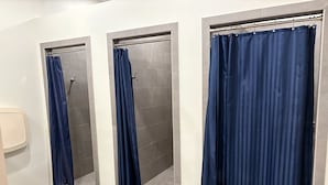 A bathroom with three shower stalls, each with a blue curtain. - RV Resort, Back-In Full Hookup, 3 Pools, Snowbirds, Kids, Pets (Foley)