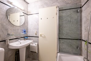Ein Badezimmer mit Waschbecken, Spiegel, Toilette und Duschbereich.