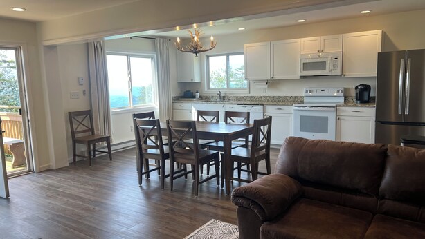 A modern kitchen with white cabinets, stainless steel appliances, and a dining area with wooden chairs. - Cozy 3-bed mtn condo in village, walkable to all! (Slaty Fork)
