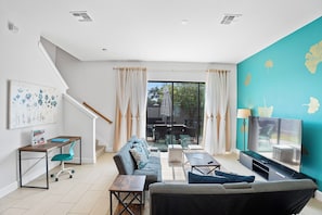 A modern living room with a sofa, coffee table, TV, and a staircase. - New Domani Resort Escape | Minutes to Disney (Davenport)