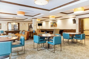 Una hall d'albergo con tavolo da biliardo, zona relax e tavolo da pranzo con sedie.
