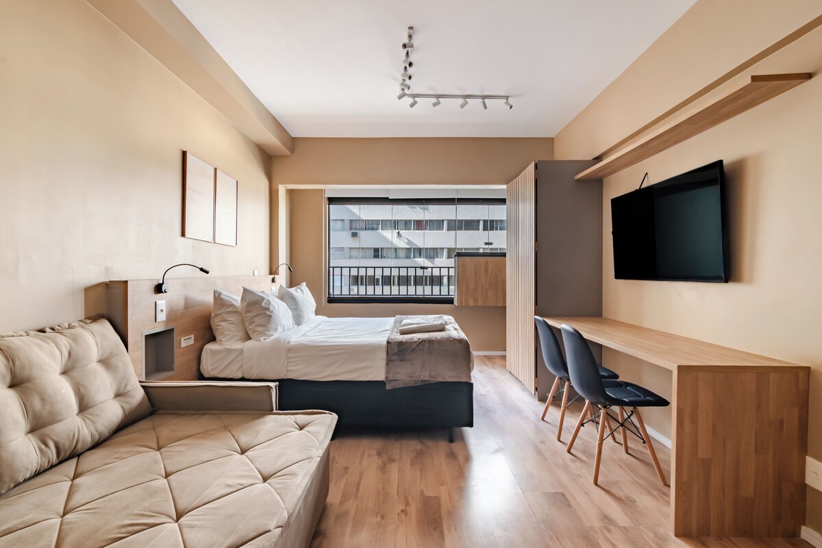 Ein modernes Schlafzimmer mit Bett, Sofa, Schreibtisch und Fernseher.