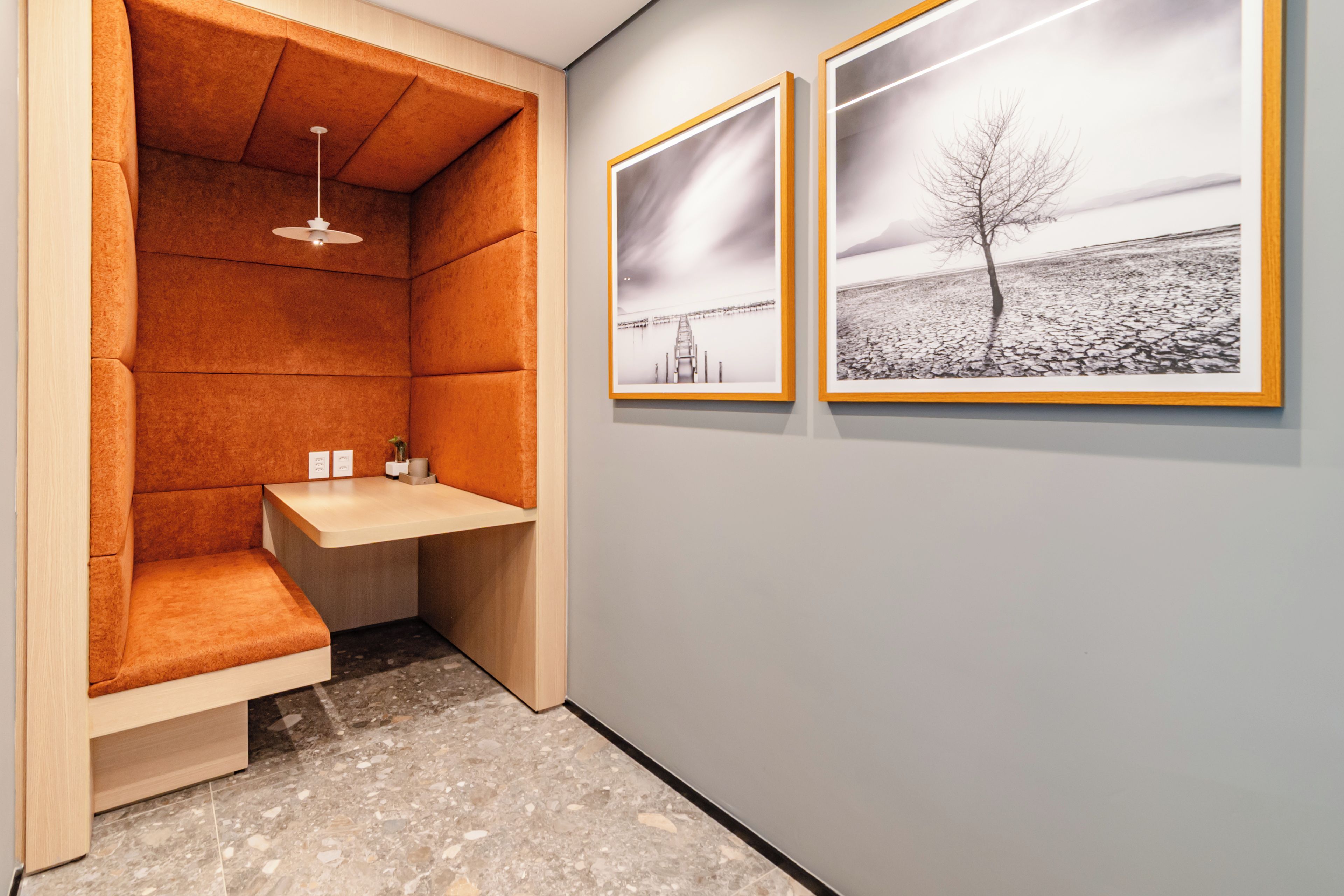 A small bathroom with a bench, a sink, and a ceiling light. There are two framed pictures on the wall.