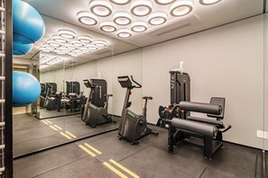 Ein Fitnessraum mit Trainingsgeräten, einem großen Spiegel und einem blauen Trainingsball.