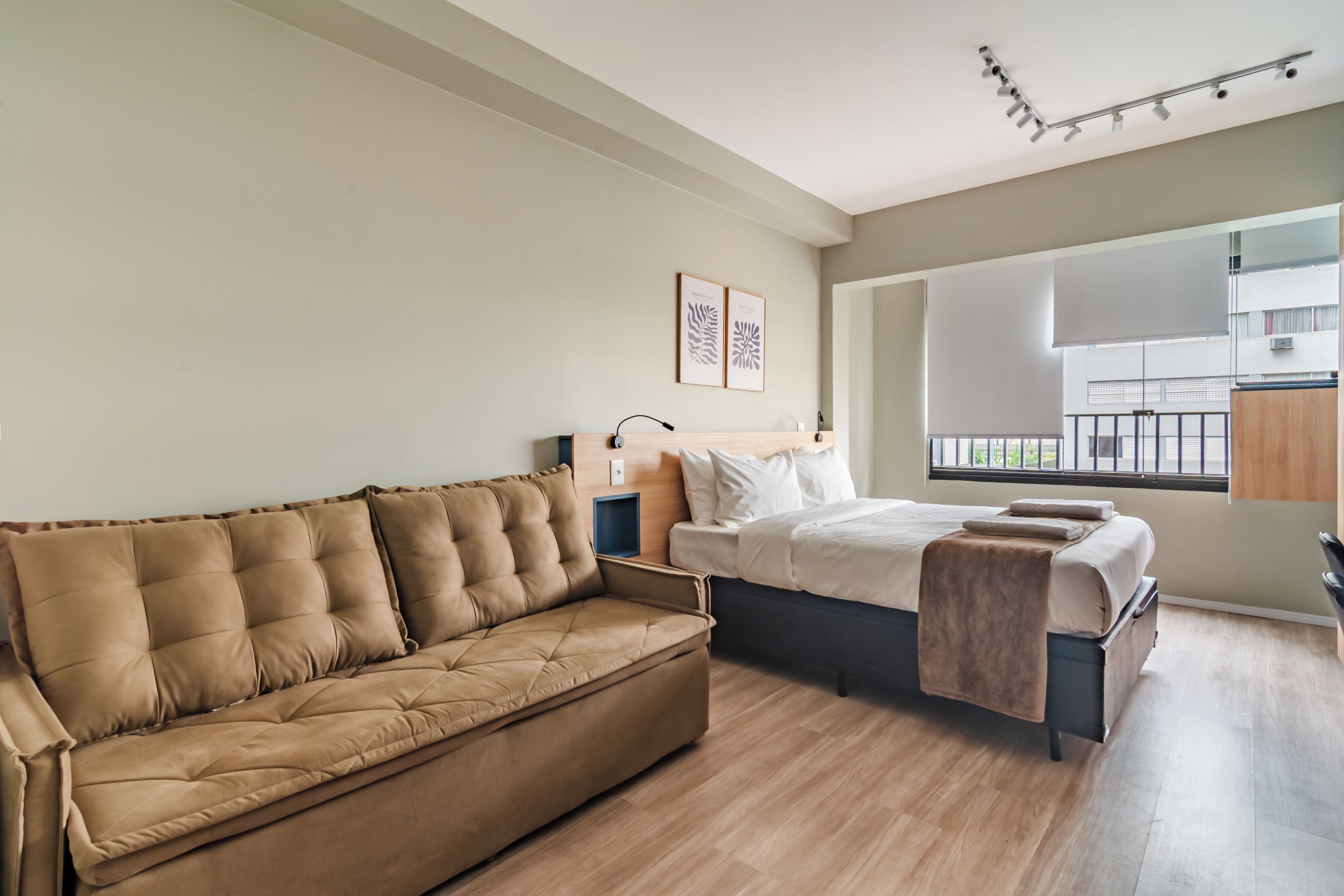Een moderne slaapkamer met een bank, een bed en een raam met uitzicht.