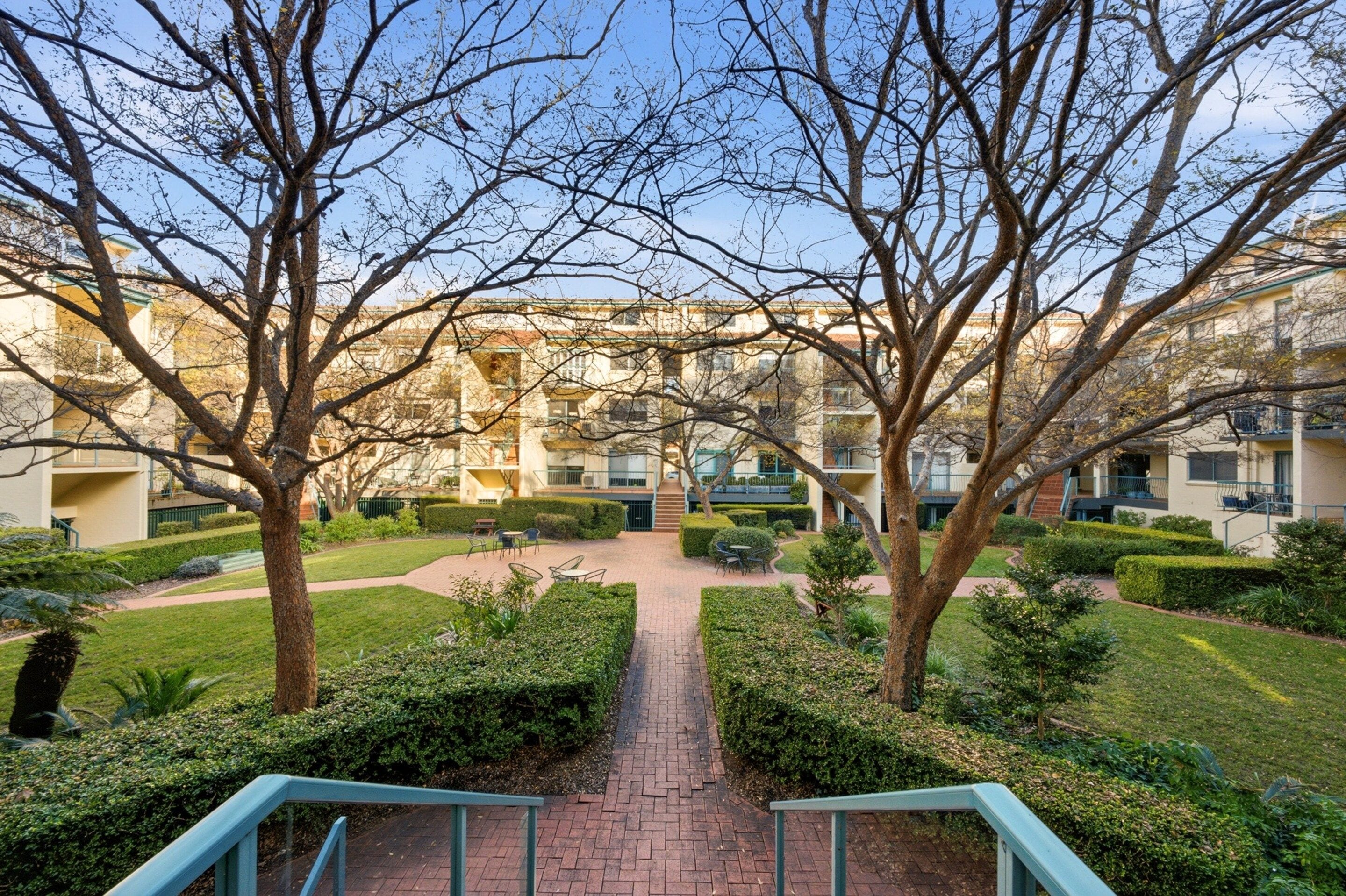 A pathway leading to a courtyard with a building in the background.