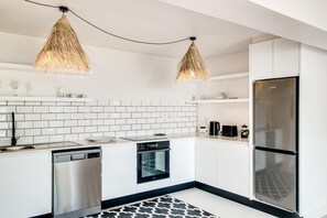 Eine moderne Küche mit weißen Schränken, einem Edelstahlkühlschrank, einer Spülmaschine und einem eingebauten Backofen.