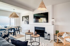 Ein modernes Wohnzimmer mit Kamin, Sitzgruppe und Essbereich mit Aussicht.