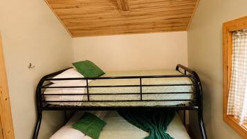 A bunk bed with a wooden ceiling, a window with a checkered curtain, and a wooden floor.