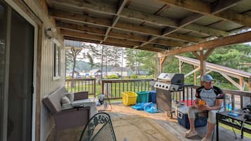 Un espacio al aire libre techado con una parrilla, asientos y vistas del entorno.
