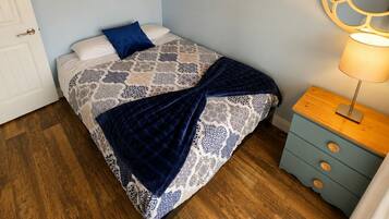 A bedroom with a bed, a nightstand, a lamp, and two wall art pieces.