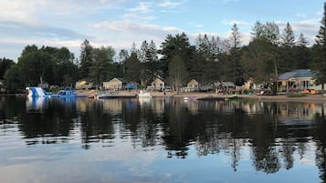 A lakeside view with boats, cabins, and a forested background.