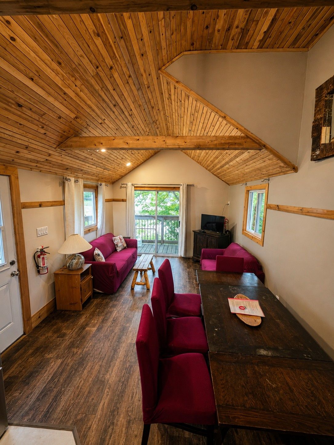 Une pièce chaleureuse avec un plafond en bois, un canapé, une table à manger et un téléviseur.