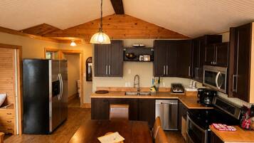 A modern kitchen with a wooden ceiling, dark cabinets, stainless steel appliances, and a central island.