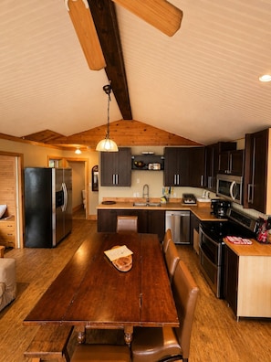 A modern kitchen with a wooden ceiling, dark cabinets, stainless steel appliances, and a central island. - Echo Beach Cottage Resort (Magnetawan)