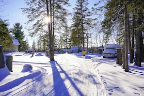 A snow-covered road with houses on either side, a truck parked on the right, and a sign that reads 'Echo Beach'. - Echo Beach Cottage Resort (Magnetawan)