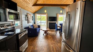 A modern kitchen with a large refrigerator, microwave, and stove. There is a dining area with a table and chairs, and a blue sofa.