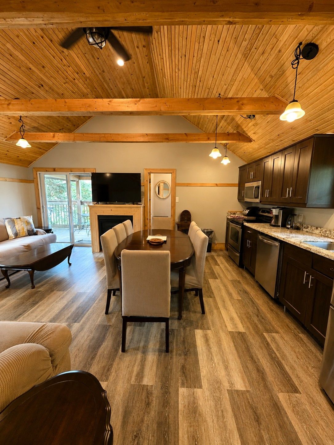 A modern kitchen with wooden beams, a dining area with a round table, and a fireplace.