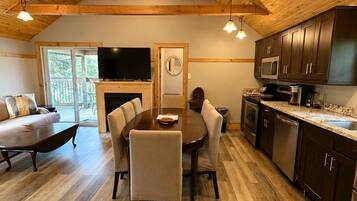 A modern kitchen with wooden beams, a dining area with a round table, and a fireplace.