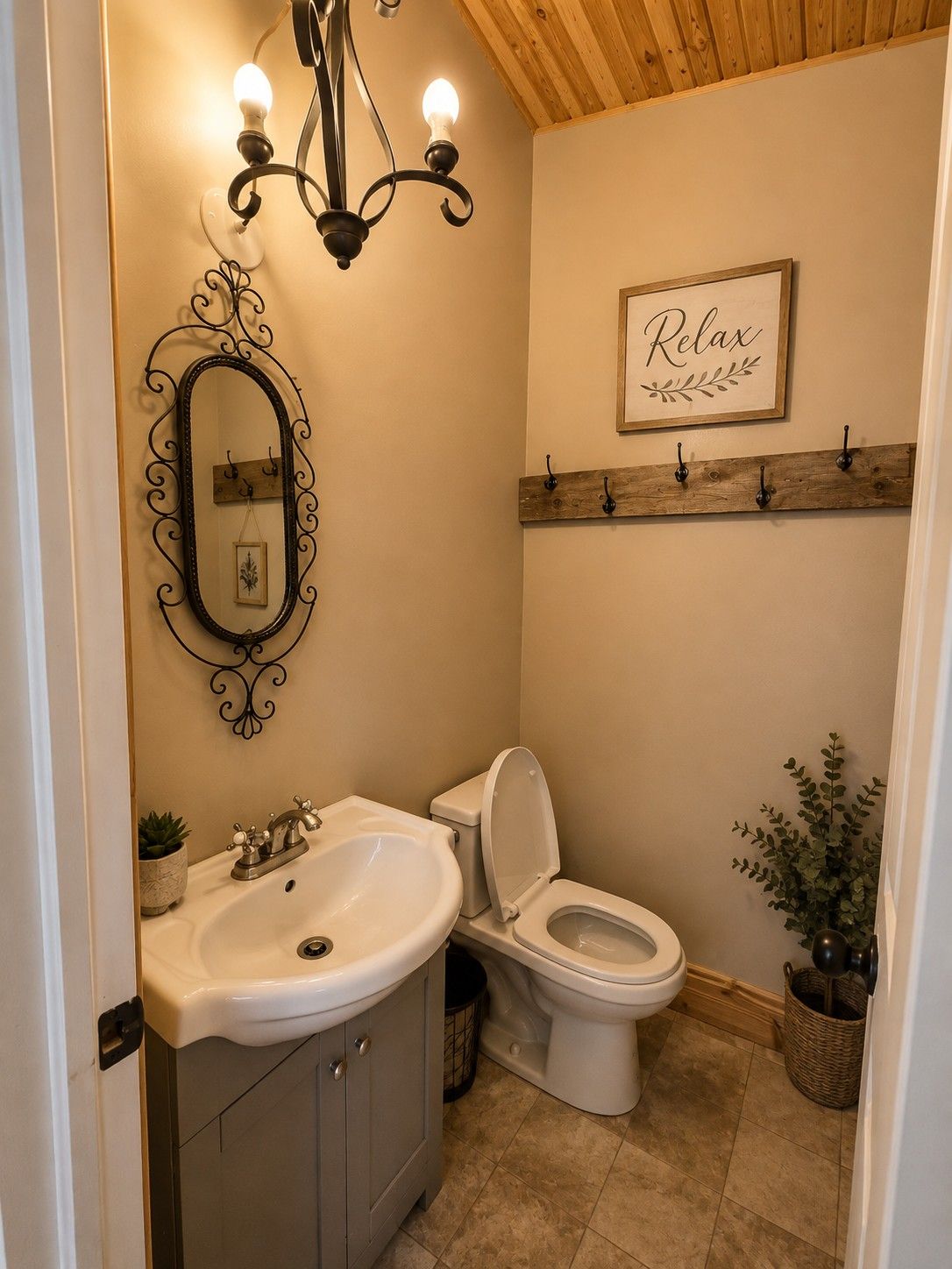 A bathroom with a white sink, a toilet, a mirror with a decorative frame, a chandelier, and a 'Relax' sign on the wall.
