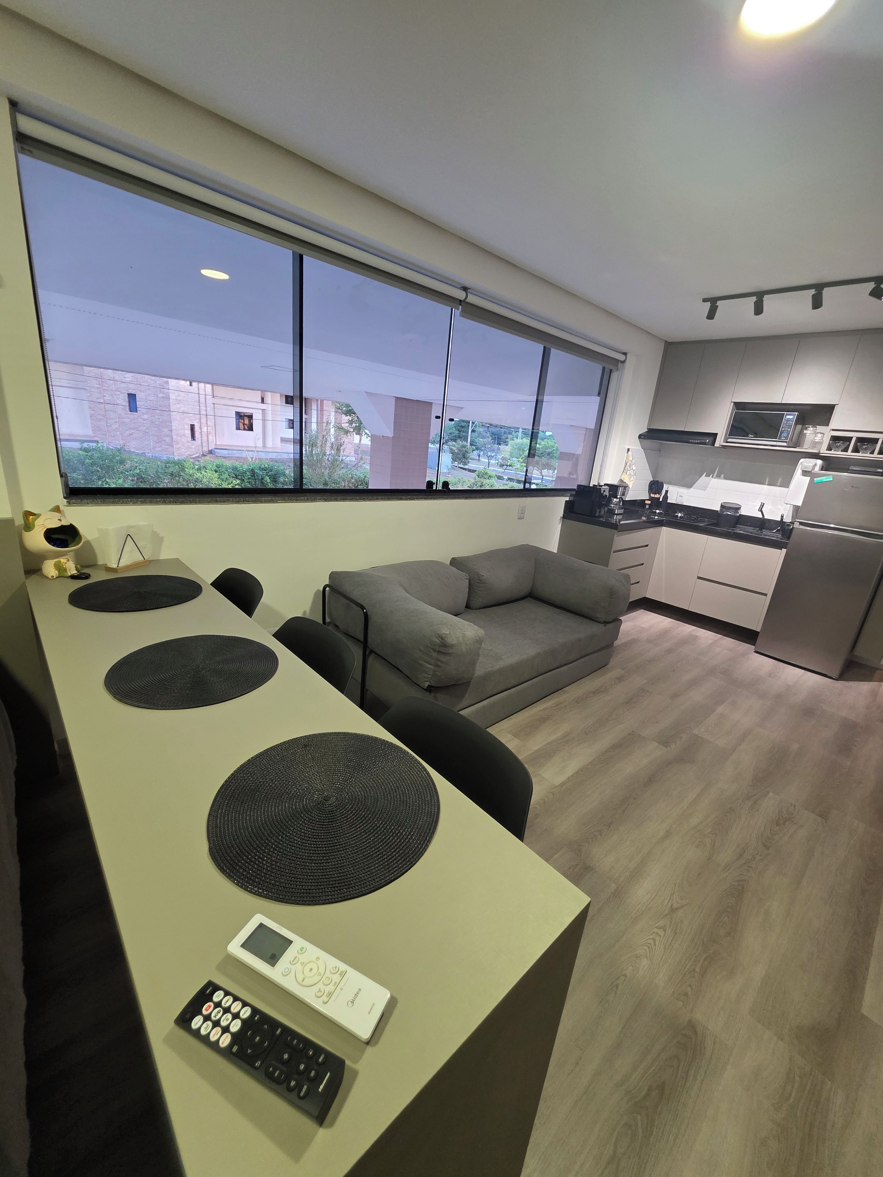 Um espaço de estar moderno com cozinha, área de jantar com mesa e cadeiras, e um sofá.