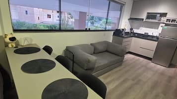 Um espaço de estar moderno com cozinha, área de jantar com mesa e cadeiras, e um sofá.