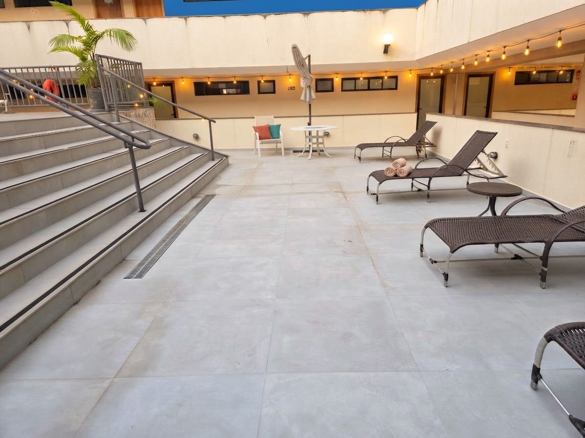 A spacious indoor area with a staircase, lounge chairs, and a small table with a fan.