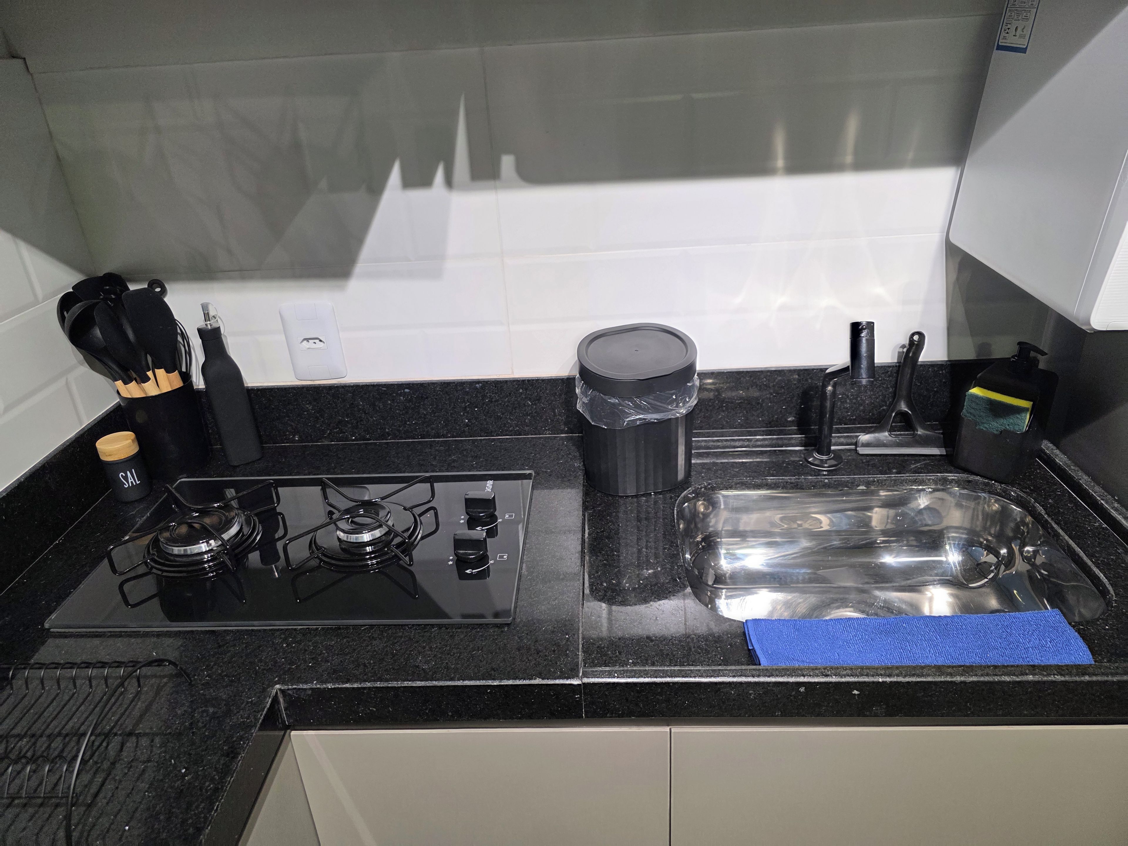 Cozinha com fogão a gás, pia e diversos utensílios.