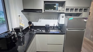 A modern kitchen with a built-in microwave, stove, and refrigerator. - Estúdio Premium ao lado do Iguatemi (Lago Norte)