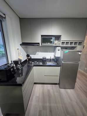 A modern kitchen with a built-in microwave, stove, and refrigerator. - Estúdio Premium ao lado do Iguatemi (Lago Norte)