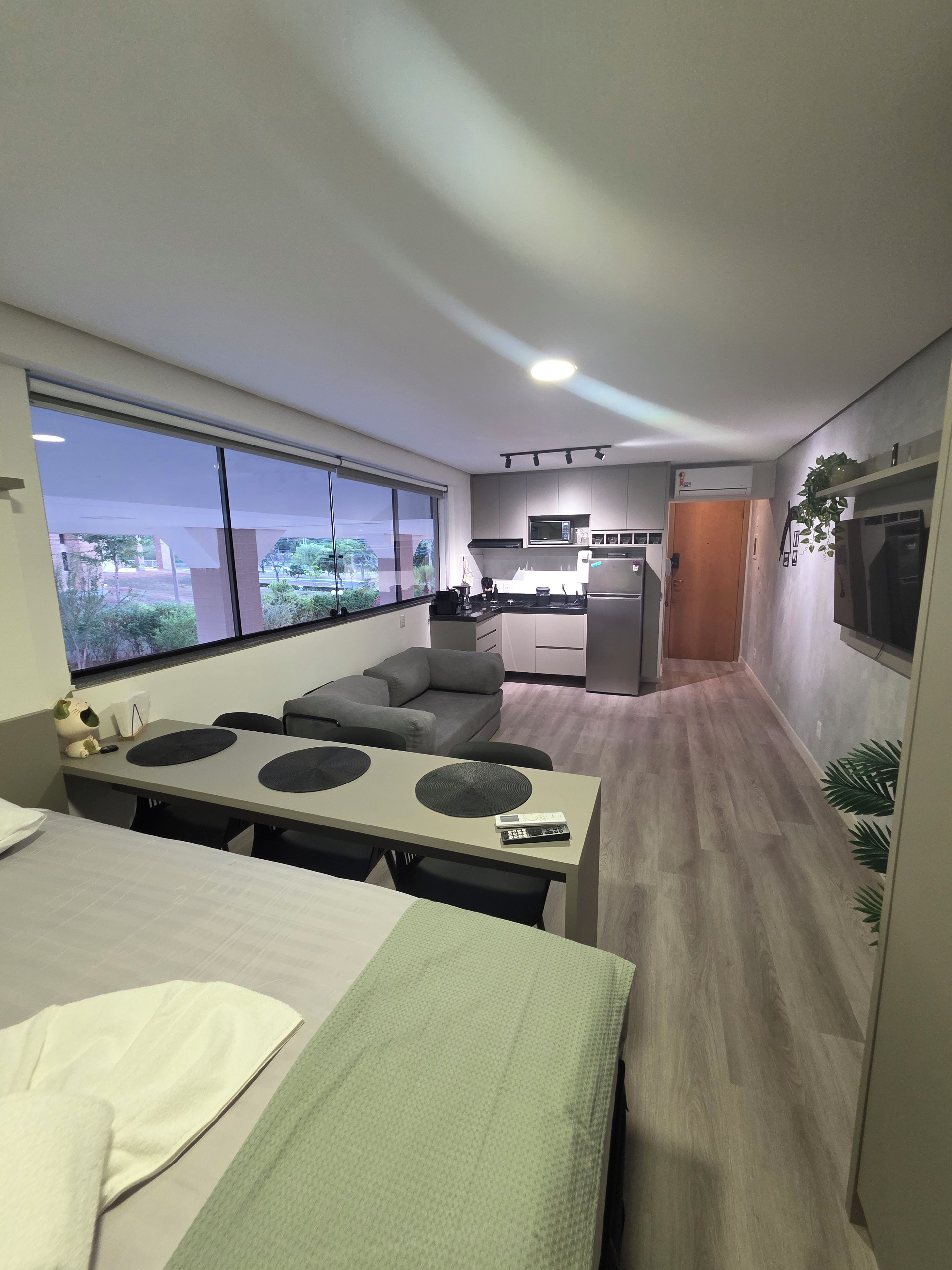 Quarto de hotel compacto com cozinha compacta, área de refeições e uma grande janela com vista para o exterior.