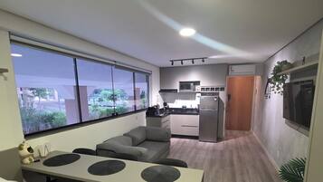 Quarto de hotel compacto com cozinha compacta, área de refeições e uma grande janela com vista para o exterior.