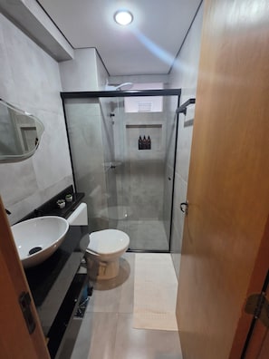 A modern bathroom with a glass-enclosed shower, a white sink, and a toilet. - Estúdio Premium ao lado do Iguatemi (Lago Norte)