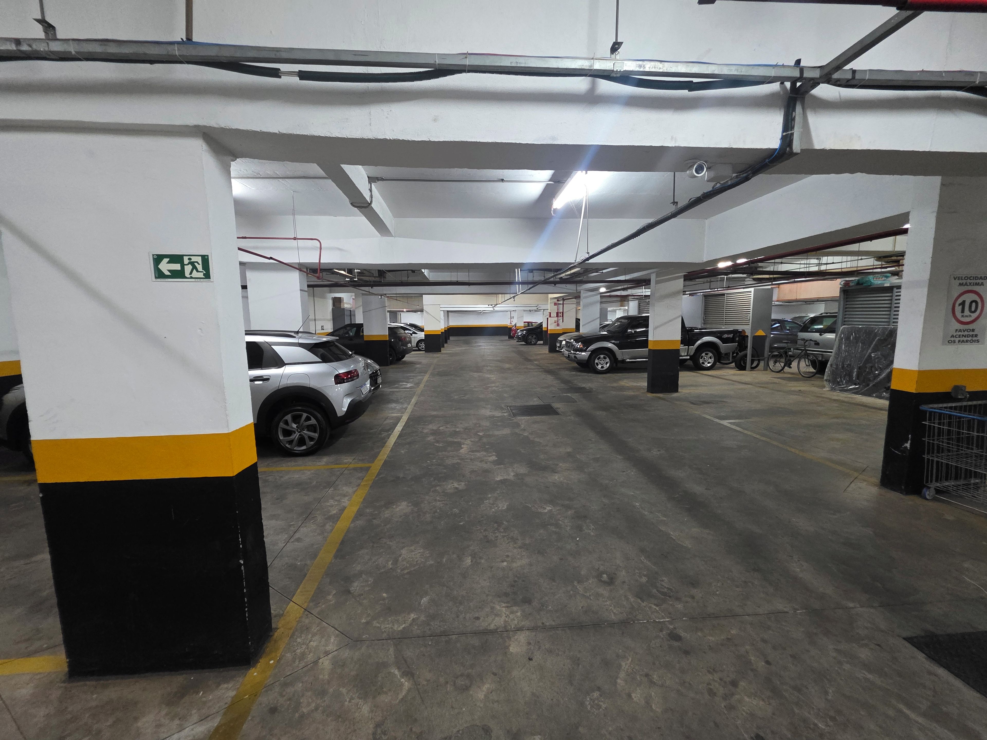 A multi-level parking garage with several cars parked, concrete floors, and structural pillars.
