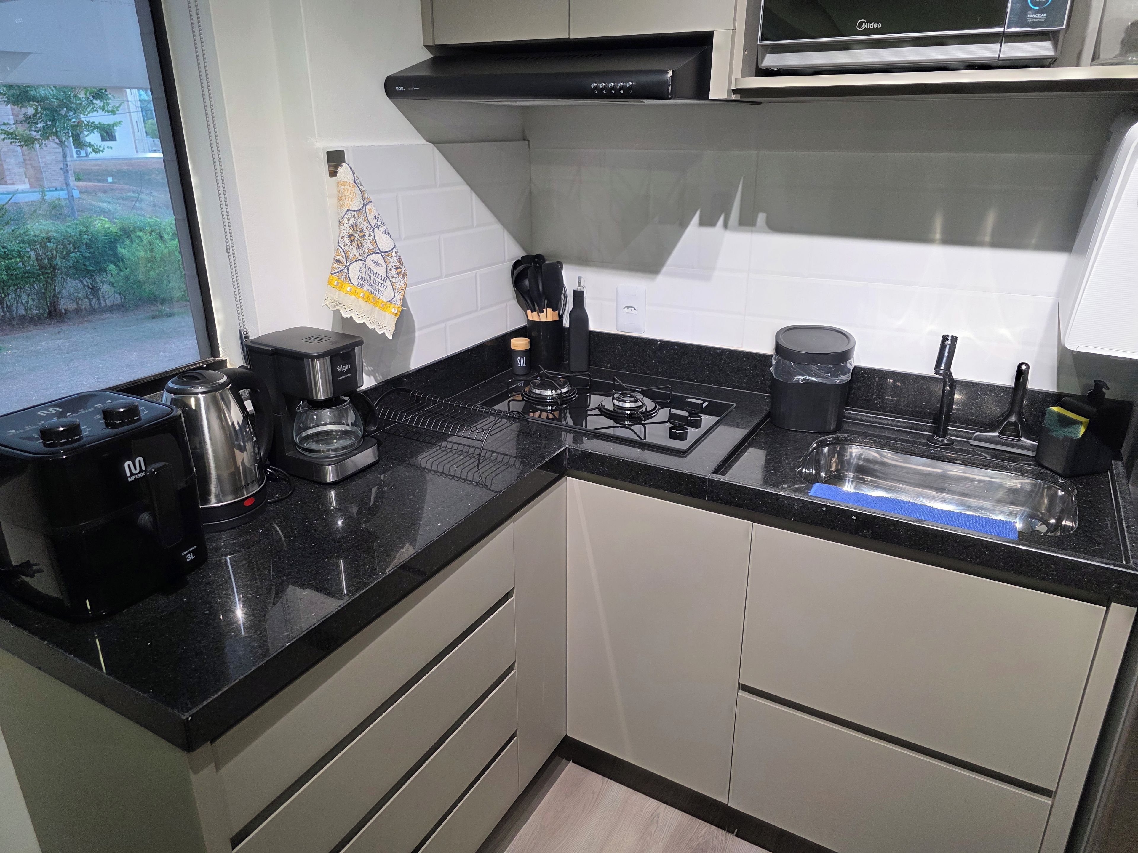 Cozinha equipada com fogão a gás, cafeteira e micro-ondas.