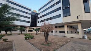 A modern building with a flat facade, multiple floors, and a letter 'F' on the side. - Estúdio Premium ao lado do Iguatemi (Lago Norte)
