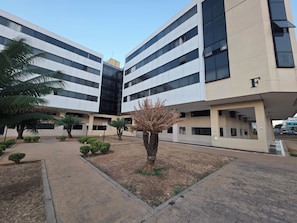 A modern building with a flat facade, multiple floors, and a letter 'F' on the side. - Estúdio Premium ao lado do Iguatemi (Lago Norte)