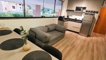 A modern kitchen with a built-in microwave, a refrigerator, and a dining area with a table and chairs.