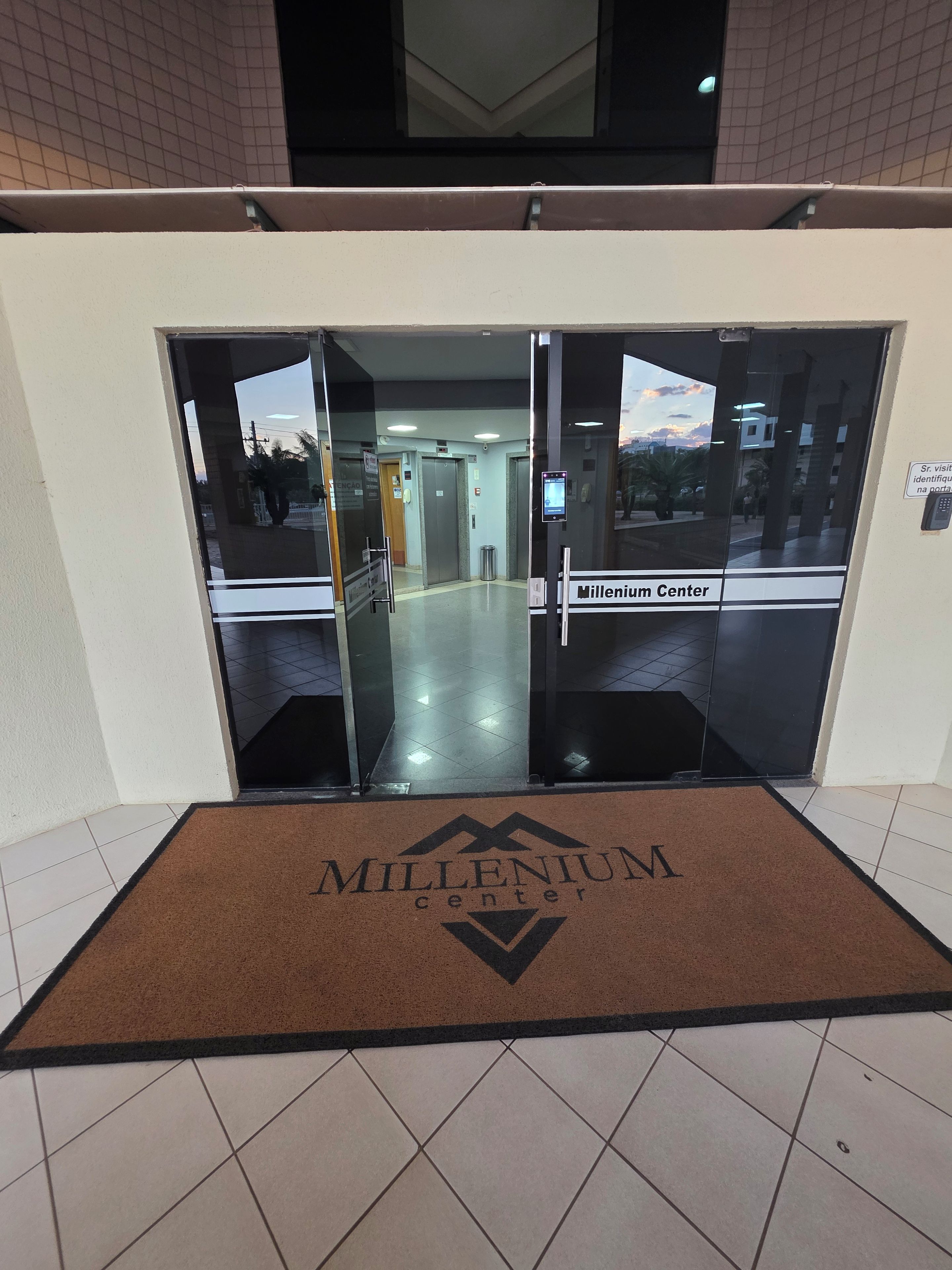A glass door entrance to a building labeled 'Millennium Center' with a brown doormat in front.