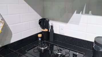 A kitchen with a black stove, white tiled backsplash, and a black range hood.