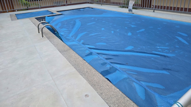 A swimming pool with a metal safety railing and a blue pool cover. - Estúdio Premium ao lado do Iguatemi (Lago Norte)
