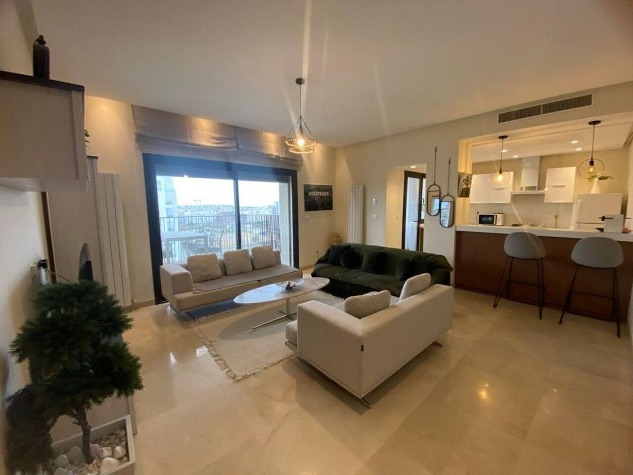 A modern living room with a sofa, a coffee table, and a dining area with a bar.