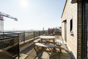 A rooftop terrace with a table and chairs, a brick building, and a view of the cityscape. - Penthouse by the Sea With Stunning Rooftop Views (Blankenberge)