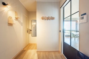 A hallway with a wooden floor, a door, a mirror, and a wall-mounted light fixture. - Penthouse by the Sea With Stunning Rooftop Views (Blankenberge)